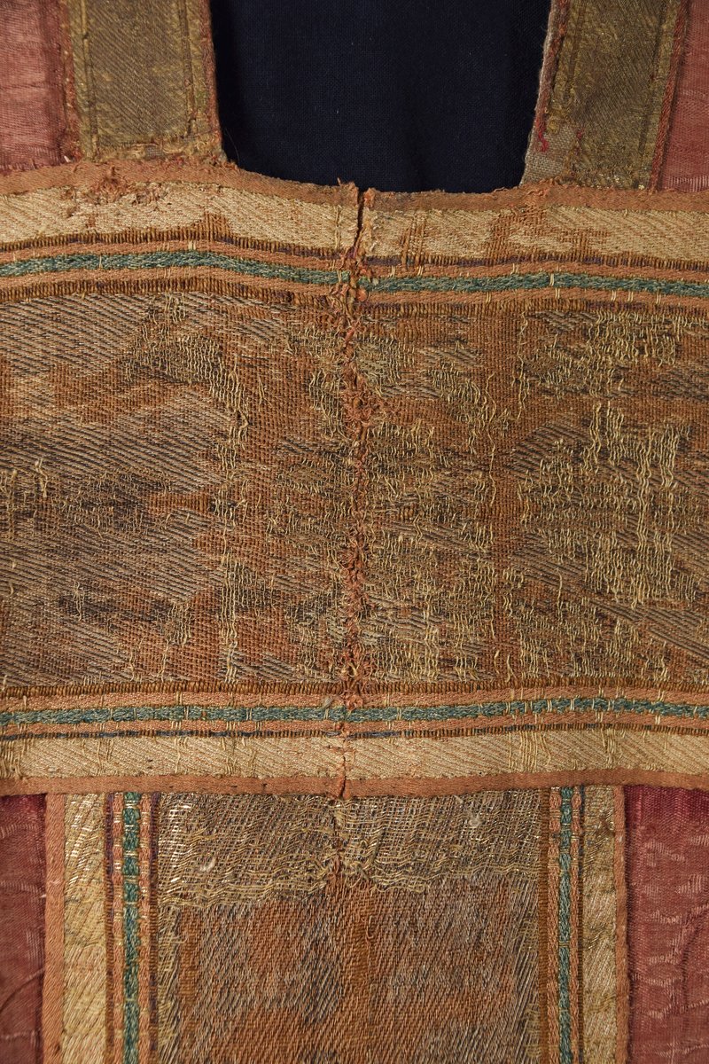 Klockformad mässhake, så kallad casula, av blåaktigt röd samitum med rektangulär halsringning. Ryggsidan prydes med en mittbård bestående av mönstervävda band, på framsidan bildar bandet ett T-kors. Ett 30-tal broderade figurer, bl a Kristus, Maria, apostlar, helgon och änglar. Varje figur är namngiven. Mellan figurerna är små klöverblad broderade, i silke och guldtråd. Mässhaken är fodrad med ofärgat linne.

Konserverad 1982-1985 av RAÄ. Hopfogad av antependium nr 1495 och mässhake 1494.

Enligt liggaren:
"Messhake, liffergad med kors framst. Jesus och Maria omgifven af apostlarne samt englakor., från 1200-talet"
Litteratur:
"Medeltida vävnader och broderier i Sverige",  A. Branting och A. Lindblom. 1928/29
"Medeltida textilier i Skara Domkyrka", Skara I, Inger Estham. 1986