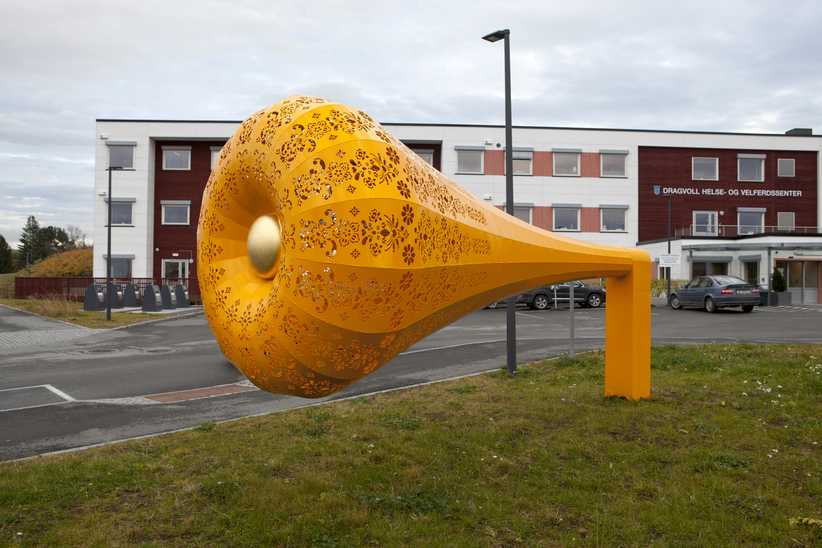 Gul skulptur formet som en trakt, en tut, med kniplingemønter utskjært i overflaten. 