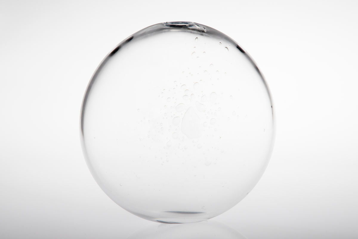 Vase i klart glass. Flattrykt kuleform med liten oval bunnflate og liten uregelmessig åpning. Uregelmessige luftbobler som dekor.