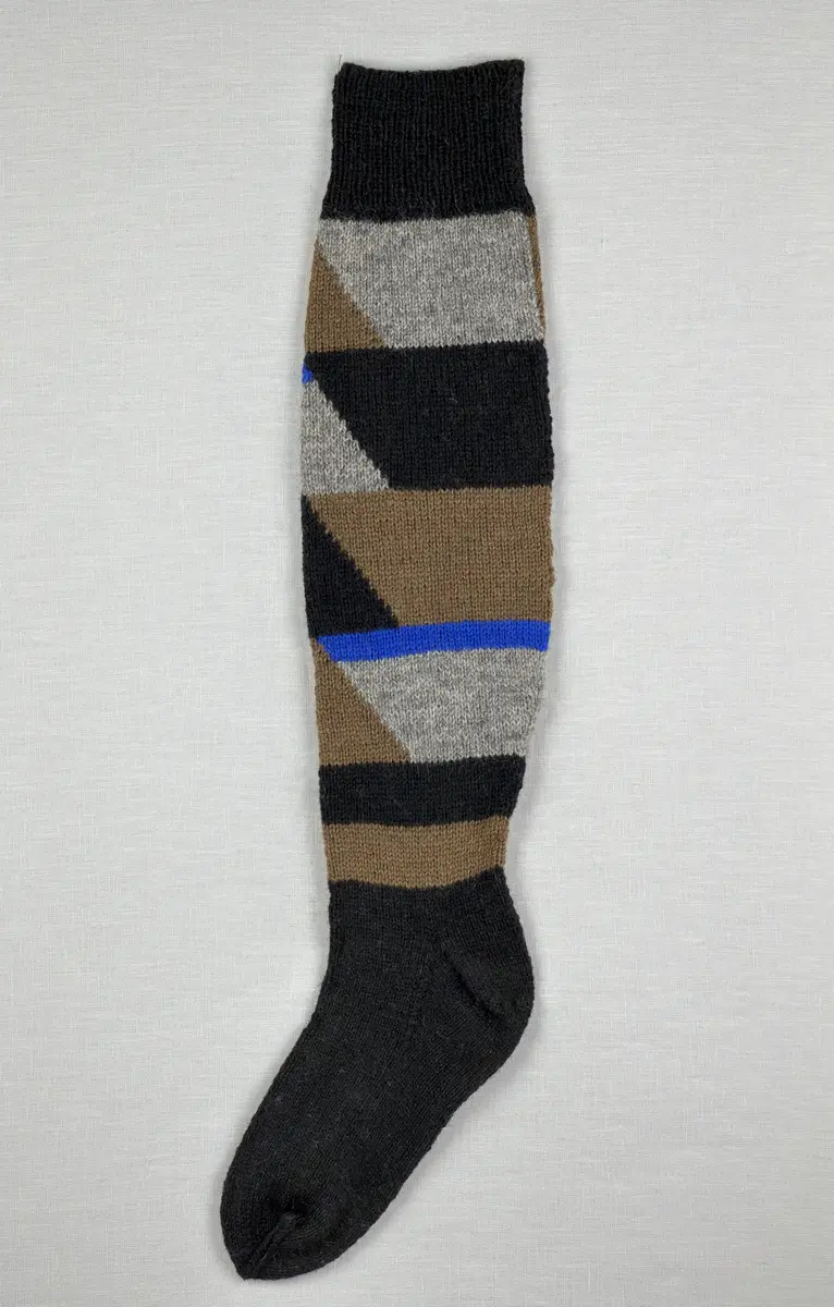 En stickad socka, med mudd i 1-1 resår (1 rät och 1 avig maska), skaft mönstrat med intarsia och fot i slätstickning, av 2-trådigt ullgarn.
