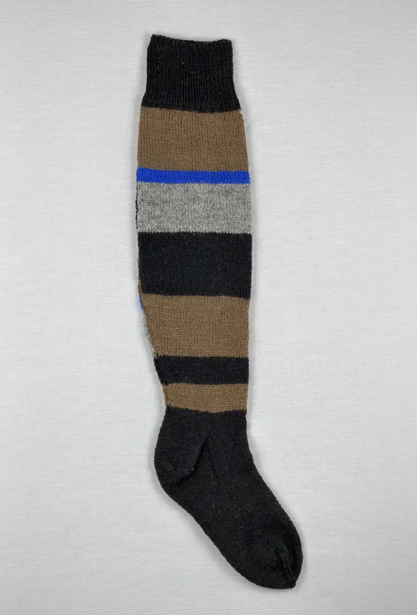 En stickad socka, med mudd i 1-1 resår (1 rät och 1 avig maska), skaft mönstrat med intarsia och fot i slätstickning, av 2-trådigt ullgarn.
