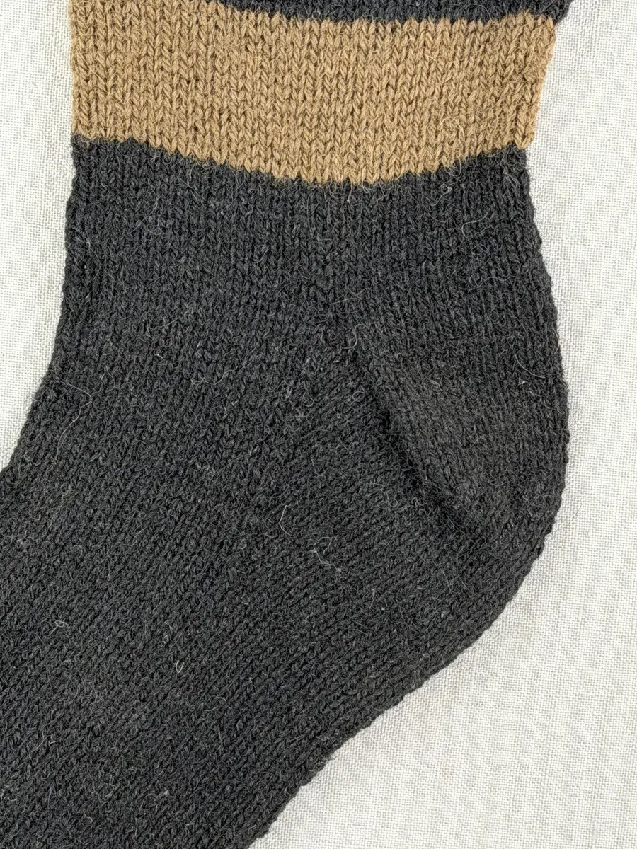 En stickad socka, med mudd i 1-1 resår (1 rät och 1 avig maska), skaft mönstrat med intarsia och fot i slätstickning, av 2-trådigt ullgarn.
