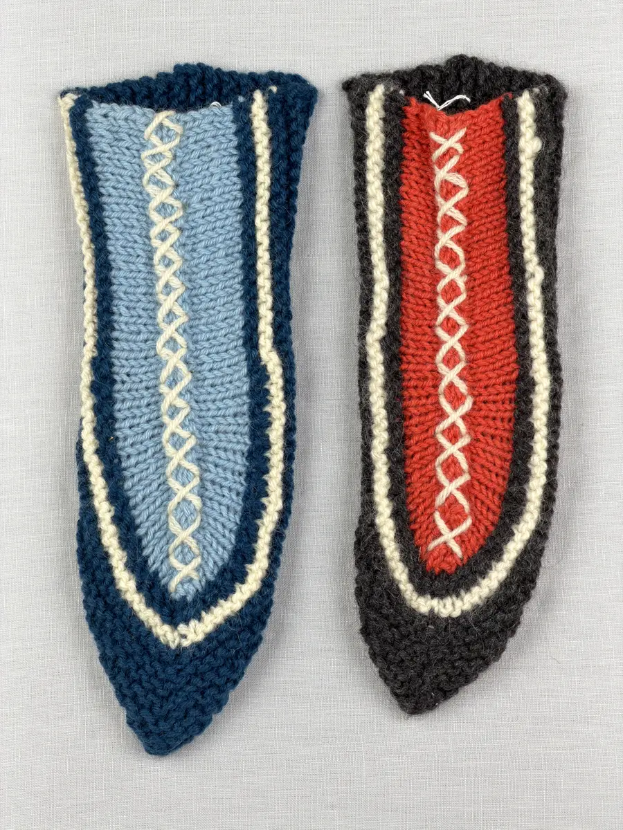 Två stickade tofflor, i slät- och rätstickning, av 3-trådigt ullgarn - Dubbelsport från Bergå Spinneri. Toffeln är hopsydd mitt fram med kaststygn och sedan dekorerad med korsstygn på rad, som ska likna en "snörning".
Gjord efter Bergå beskrivning innesockan Mysing från Bergå Färgeri & Ullspinneri, Stora Skedvi, Dalarna.