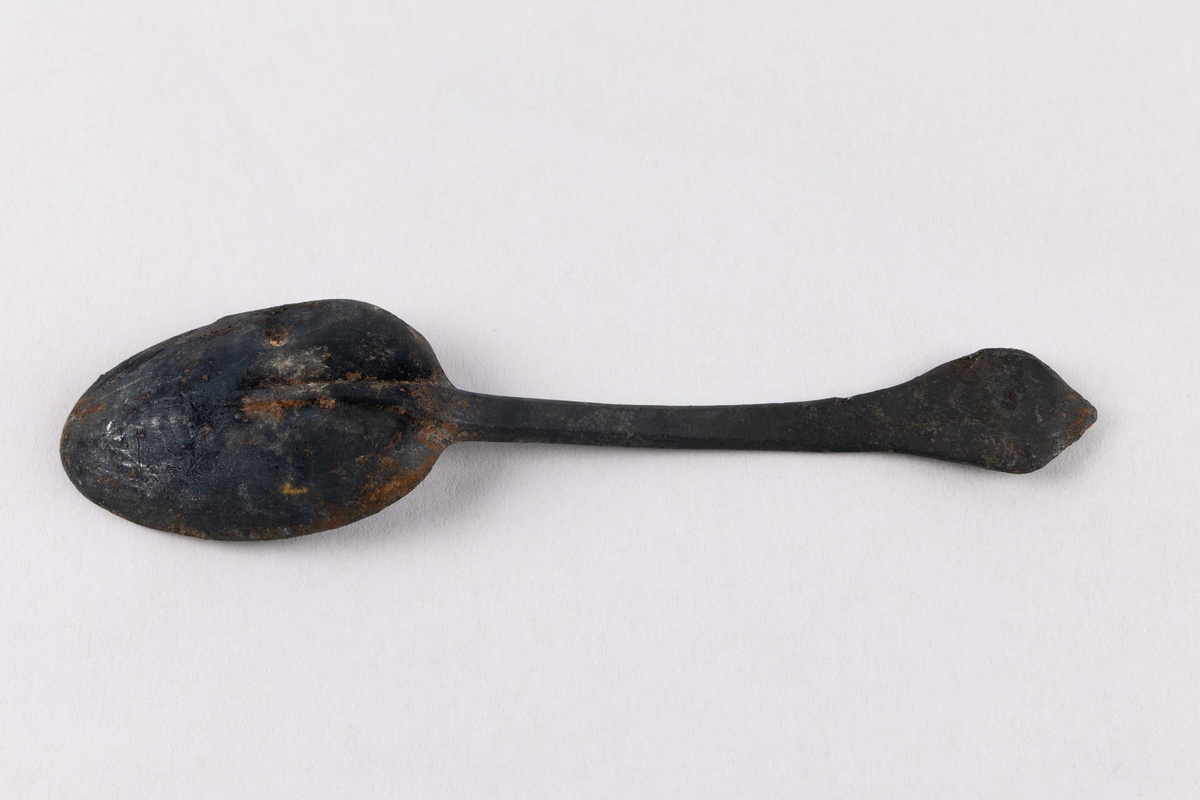 Komplett skje med hode og skaft funnet ved skipet AKERENDAM som forliste på Runde i 1725. Skaft enkelt dekorert, samt stempel på bakside av skaft.