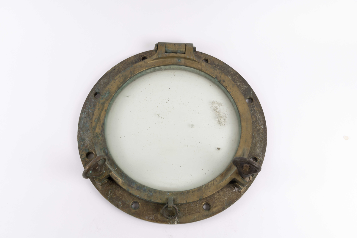 Luftkompass opphengt i slingrebøyle. Glass i topp, kompassnål mangler. Kontrollmerker innrisset i glasset.