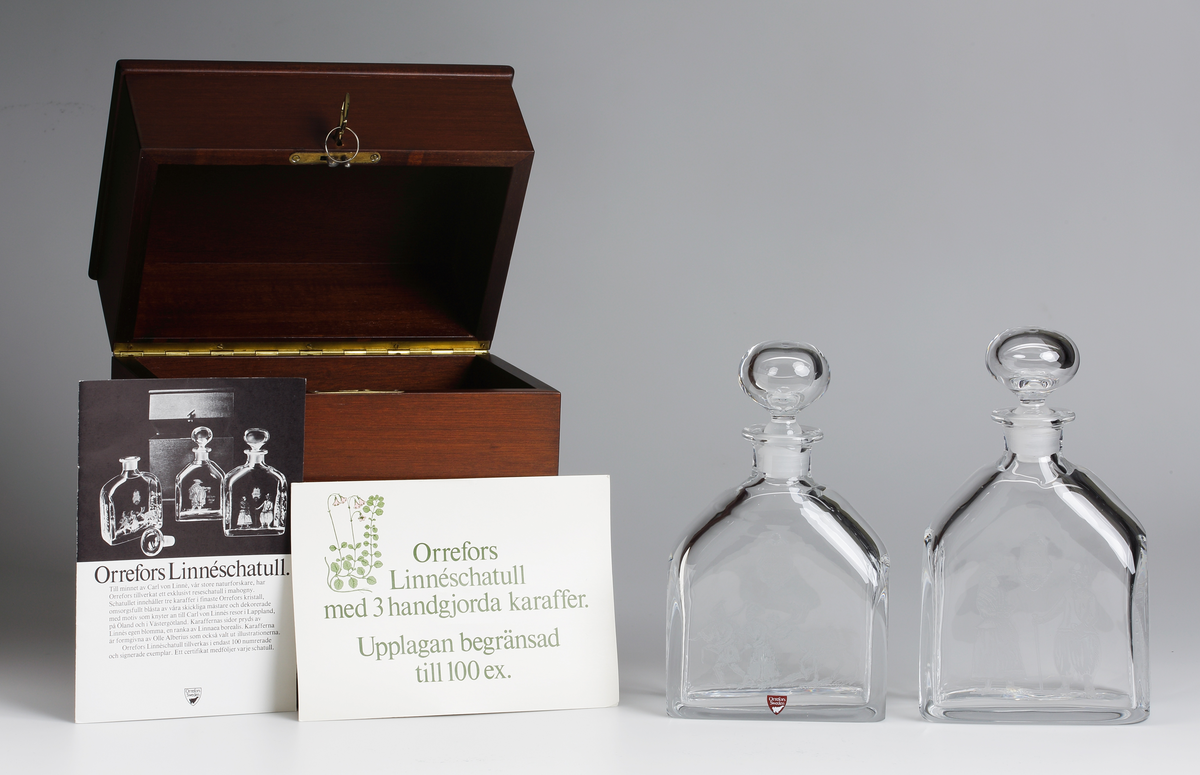 S.k. "Linnéschatull" i trä, innehållande två av tre karaffer med graverad dekor. som knyter an till Carl von Linnés resor till 
Lappland, Öland och Västergötland. Schatullet är tillverkat i 100 numrerade och signerade exemplar. Ett certifikat 
medföljer varje schatull.
Formgivare: Olle Alberius.