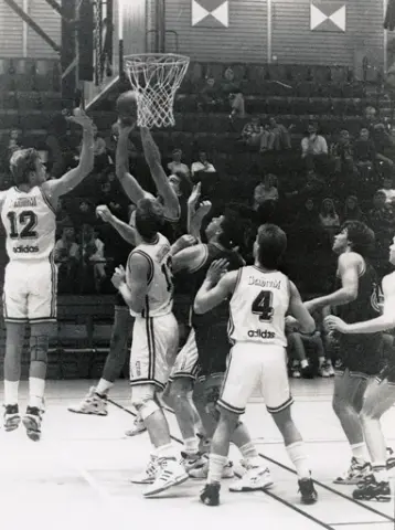 Kvarnby Basket spelar match i Mölndals idrottshus/Aktiviteten, år 1993. Motståndarlag och slutresultat är okända.