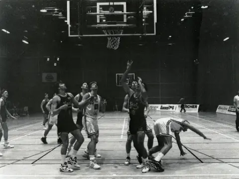 Kvarnby Basket spelar match i Mölndals idrottshus/Aktiviteten, år 1993. Motståndarlag och slutresultat är okända.