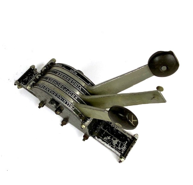 Bombväljare i metall, svartmålad. Tre spakar för val av fällningshandtag, kroppsbomber eller vingbomber -  säkrad, blind, armerad. Bakelitknopp på handtagen.