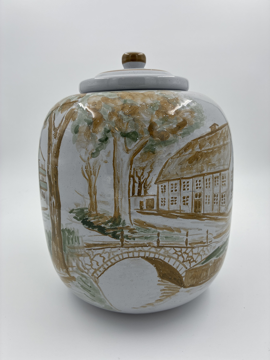 Urna med lock. Vitglaserad med handmålat motiv föreställande Alingsås fattigstuga, fana för Alingsås arbetarekommun och ålderdomshem.