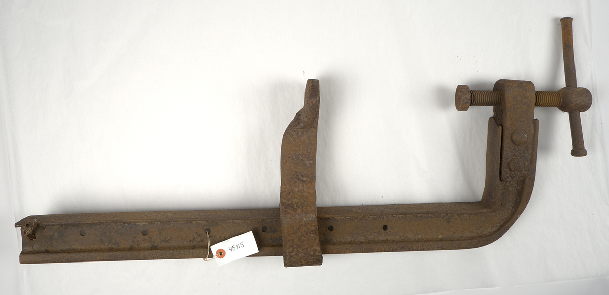 Skruvtving av järn till båtbygge från 1950-talet. Ca 110 cm lång. Rostig. 

Troligen ett hemmabygge. För att hålla anhållet på plats så används en böjd spik.