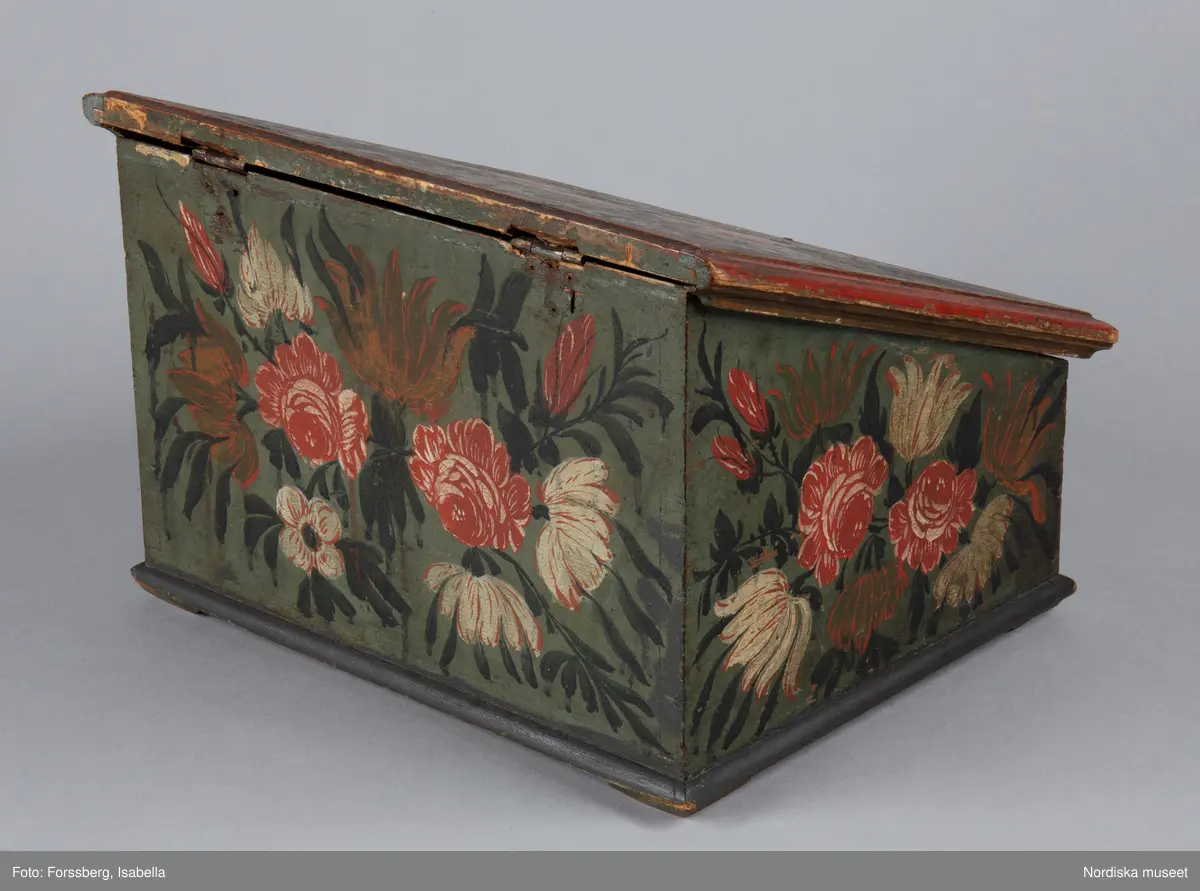 Inventering Sesam 1997-1998:
B 30, Djup 23,5, H 20 cm
Skrin, nästan kvadratiskt, med pulpetlock, av barrträ. Utanpåliggande botten, fästad underifrån med skruvar (antagligen senare ditsatt). Sidorna ihopfogade genom sinkning.
Locket har skurna profillister limmade på kanterna, två enkla gångjärn fästade invändigt.
Utanpåliggande lås, låssprint av järn i locket, nyckelskylt av järn, med nyckel.
Låda som drags ut på framsidan, limmad botten, sinkade hörn, avdelad i sex fack, handtag av järnband fästat runt bottenkanten.
Utvändigt målad blomsterdekor på locket och samtliga sidor i rött, vitt, grönt och svart på blå botten, lådans förstycke målat i samma färger för att passa in med dekoren på framsidan.
Invändigt målat i vitt, locket med växtmotiv i gult samt " CJD 1791 ", även lådan vitmålad invändigt.
Skrinet har låga, trekantiga fötter av trä limmade i hörnen under botten.
Lådans botten spräckt på två ställen.
Enligt huvudliggaren innehöll skrinet en ring, två par handskar och två böcker (inv.nr. 258.413-416).
Agnetha Blomberg 1998