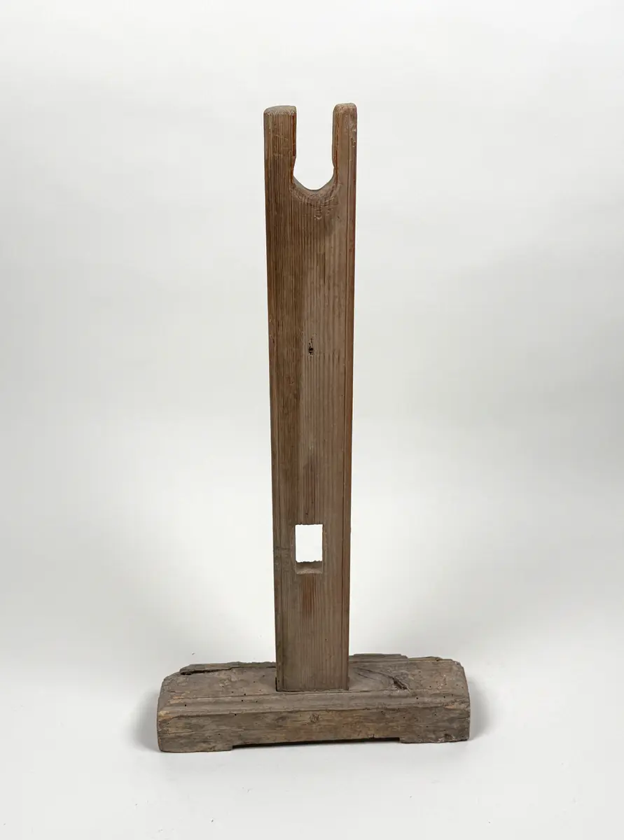 Ena benet till en benställning för bobin. Rektangulär fot med hålkärl, stående ben med fyrsidigt uttag längre ner samt U-format öppet uttag upptill. 