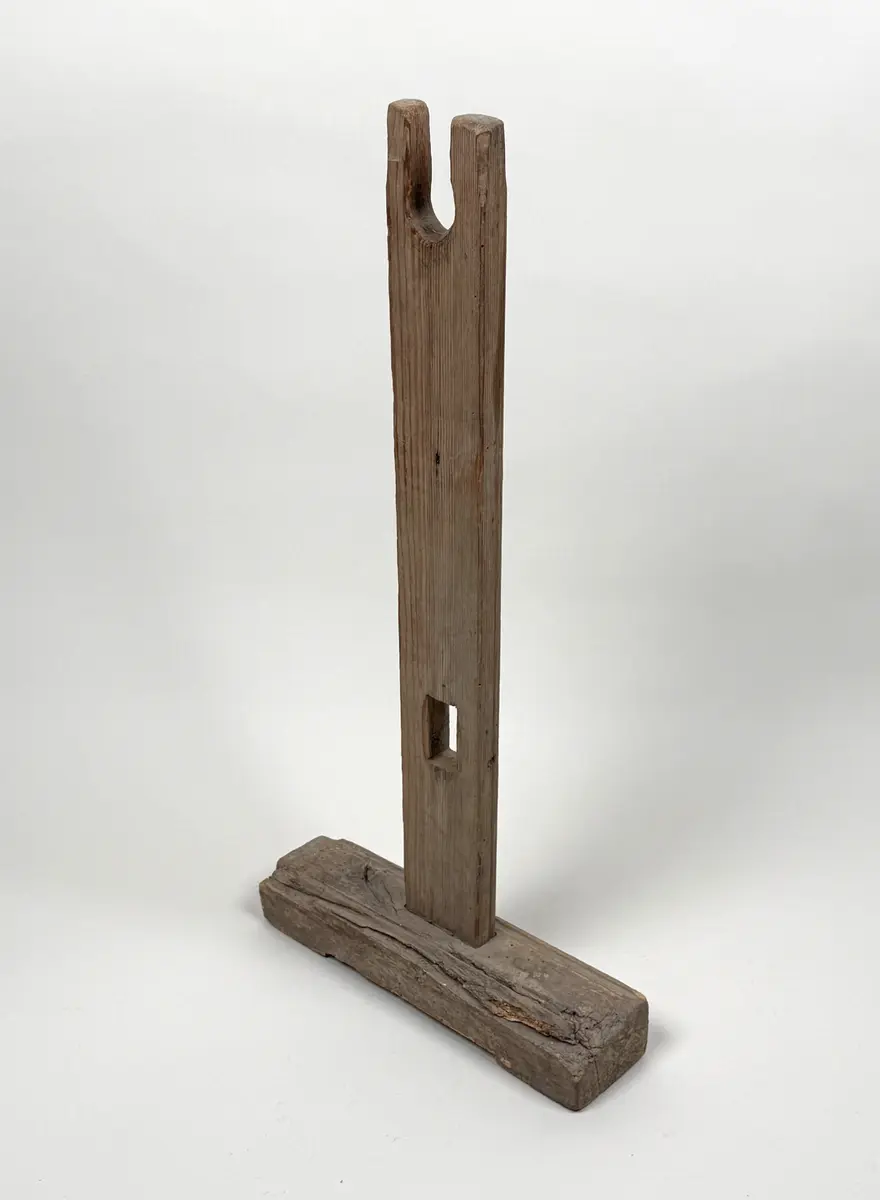 Ena benet till en benställning för bobin. Rektangulär fot med hålkärl, stående ben med fyrsidigt uttag längre ner samt U-format öppet uttag upptill. 