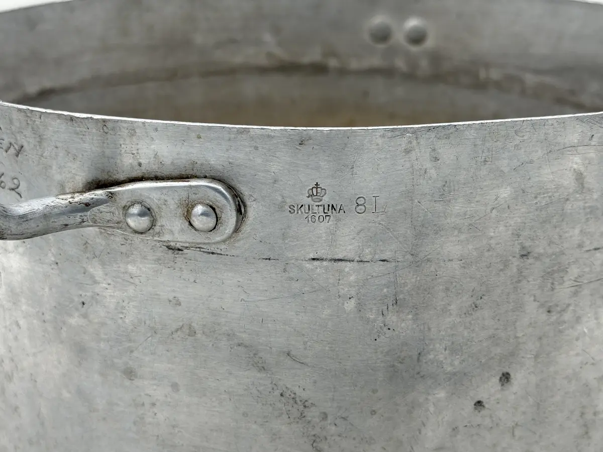 Rund kastrull av metall med två våggrepar. Stämplad Skultuna 1607 under krona samt 8L.