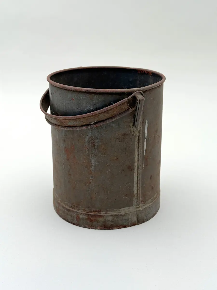 Cylindrisk hink av bleckplåt med rundad mynning. Halvcirkulär grepe. 

Lock saknas.