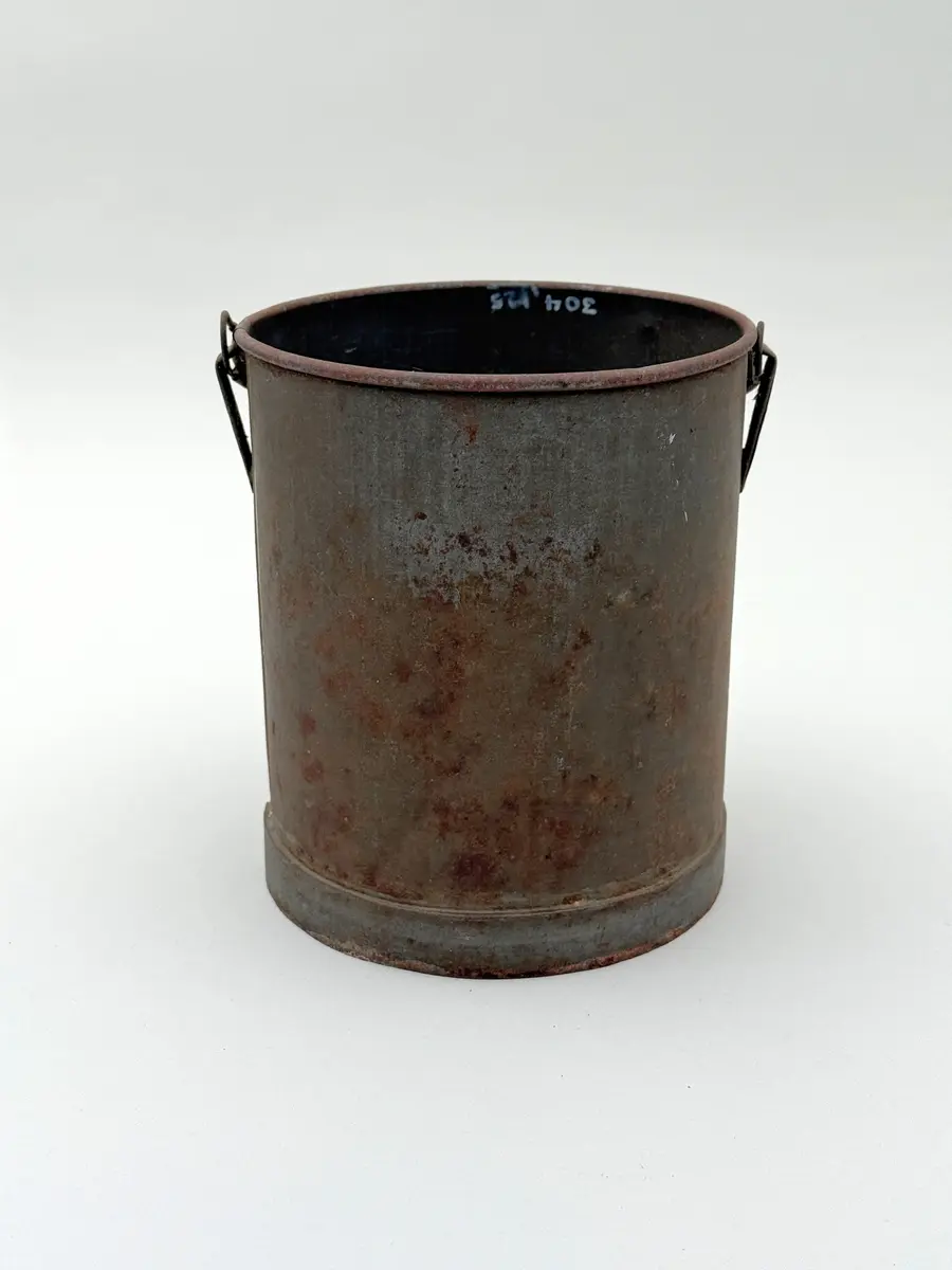 Cylindrisk hink av bleckplåt med rundad mynning. Halvcirkulär grepe. 

Lock saknas.