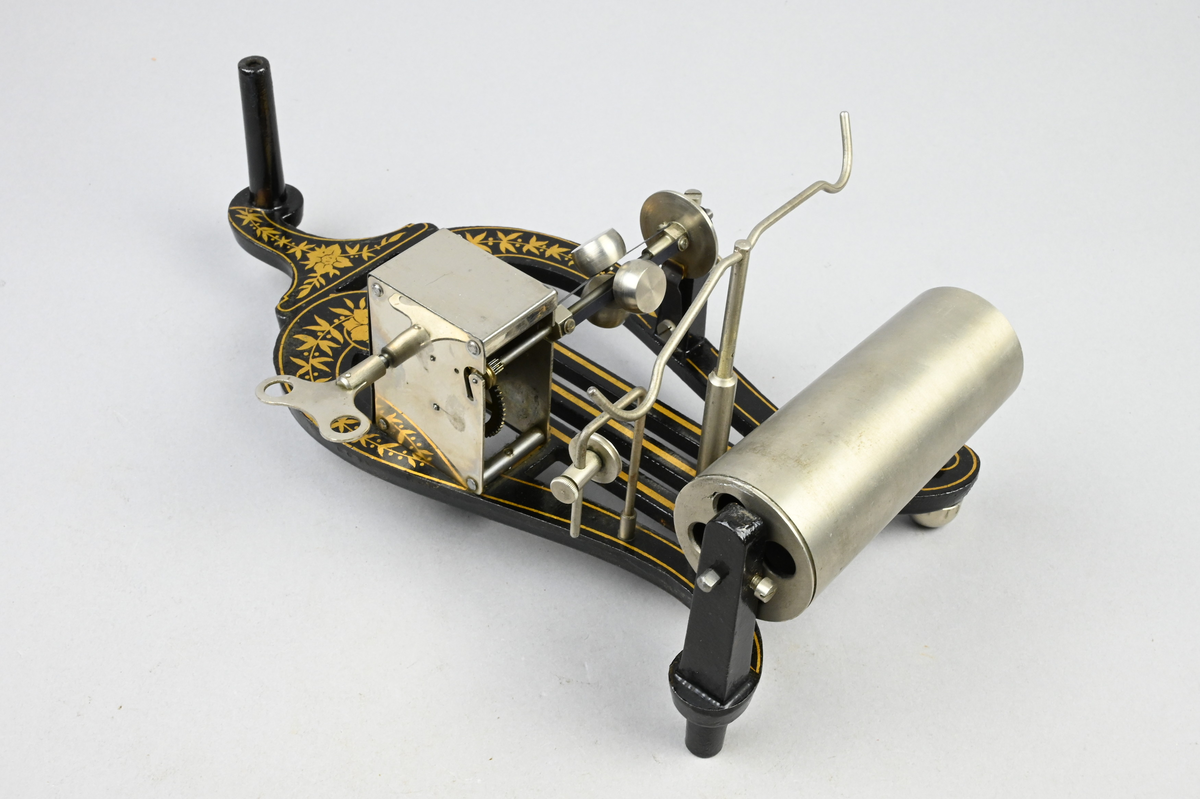 Fonograf med 6 st. vaxrullar i fodral. Fonograf med fjäderverksdriven vals för ljudrullar av Edisons mindre standardstorlek, via snörtransmission med spännare, hastighetsregulator. Konisk ljudtratt av plåt, ljuddosa med glimmermembran och stift av glas, som vid drift följer ljudspåret i rullen. Rullar av vaxmassa med 2 min. gångtid vid 160 varv/min.