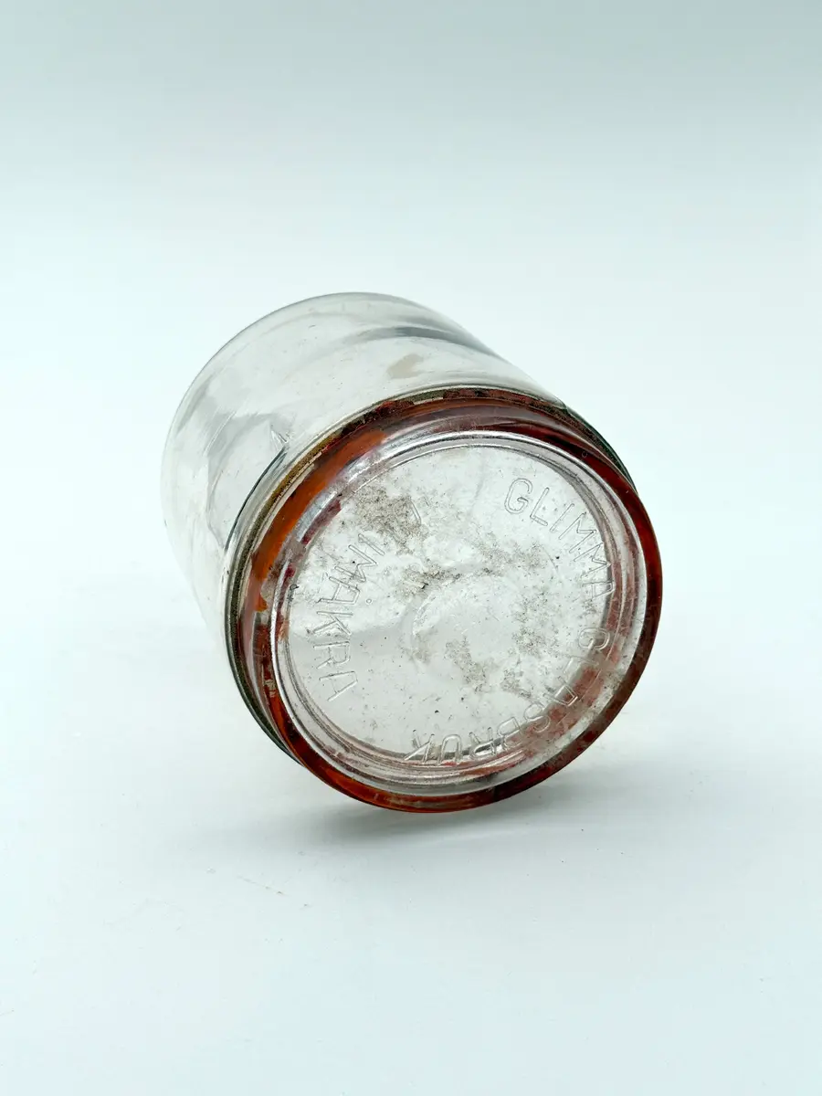 Cylindrisk burk av glas med lock och tätningsring av gummi. Locket med firmanamn i relief: GLIMMA GLASBRUK GLIMÅKRA. Botten med volymangivelse i relief: 3/4 LIT. 

Metallbygel saknas. 