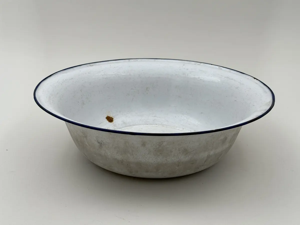 Skål av vitemaljerad plåt, utsvängd mynning, blå kant. Undersidan med frimamärke K.E.R. [Kockums Emaljerverk Ronneby] SWEDEN 32 cm. 