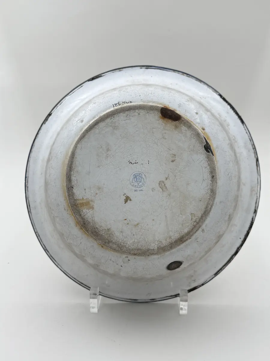 Skål av vitemaljerad plåt, utsvängd mynning, blå kant. Undersidan med frimamärke K.E.R. [Kockums Emaljerverk Ronneby] SWEDEN 32 cm. 