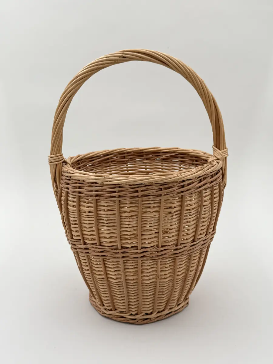 Äggkorg, handflätad av pil i två färgnyanser. Modell med ganska smal hög form. Uppsvängt handtag.