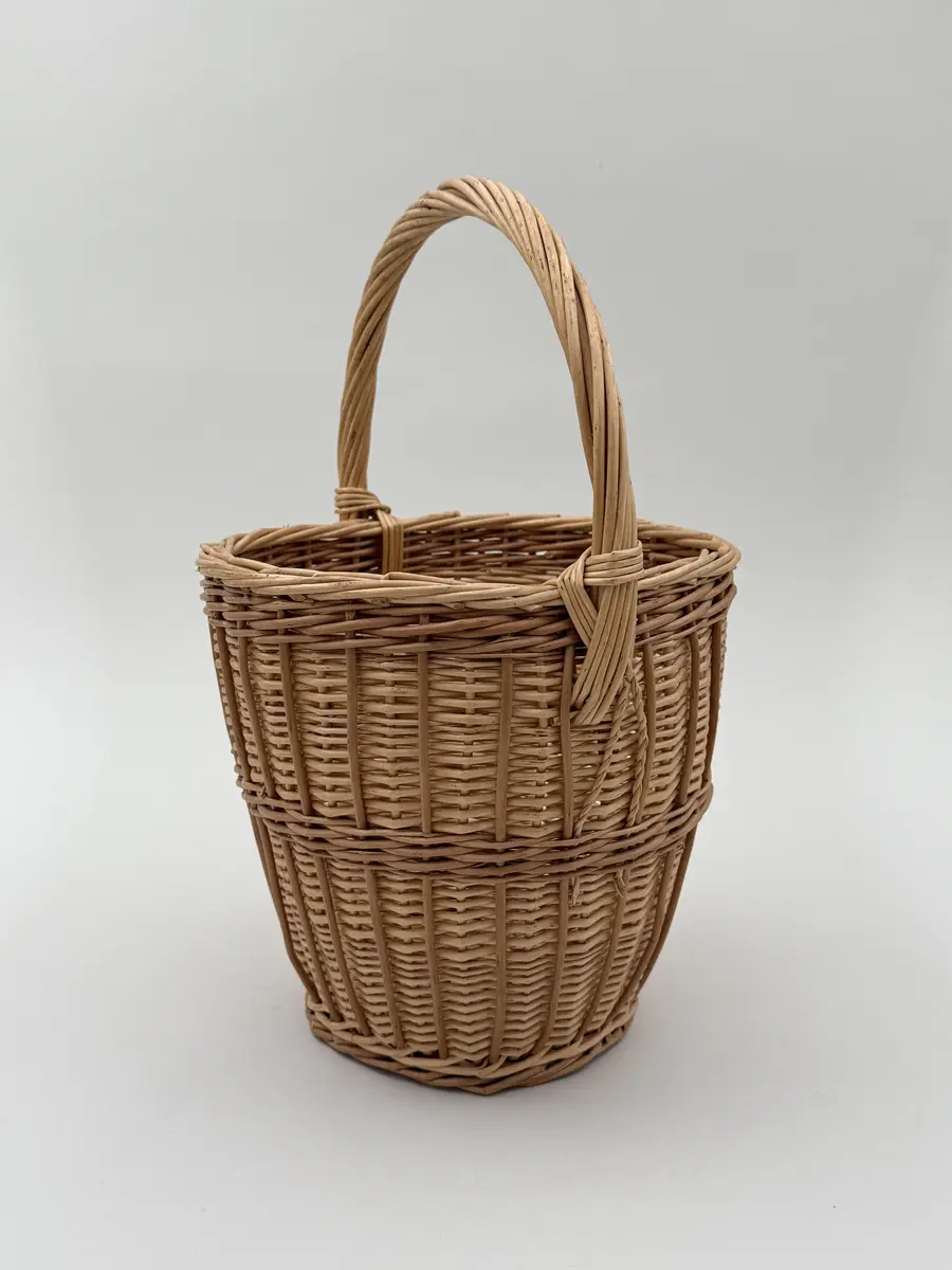 Äggkorg, handflätad av pil i två färgnyanser. Modell med ganska smal hög form. Uppsvängt handtag.