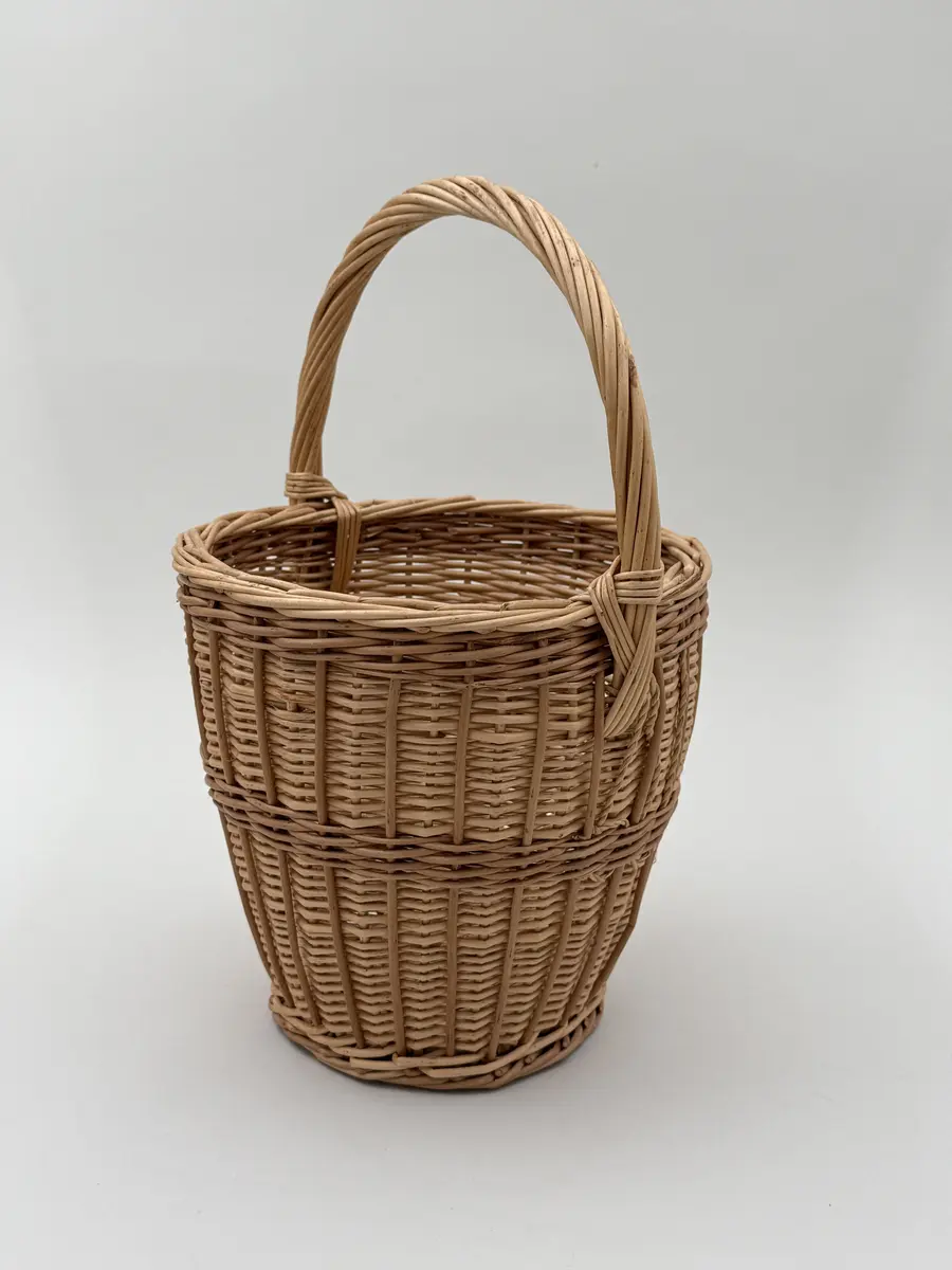 Äggkorg, handflätad av pil i två färgnyanser. Modell med ganska smal hög form. Uppsvängt handtag.