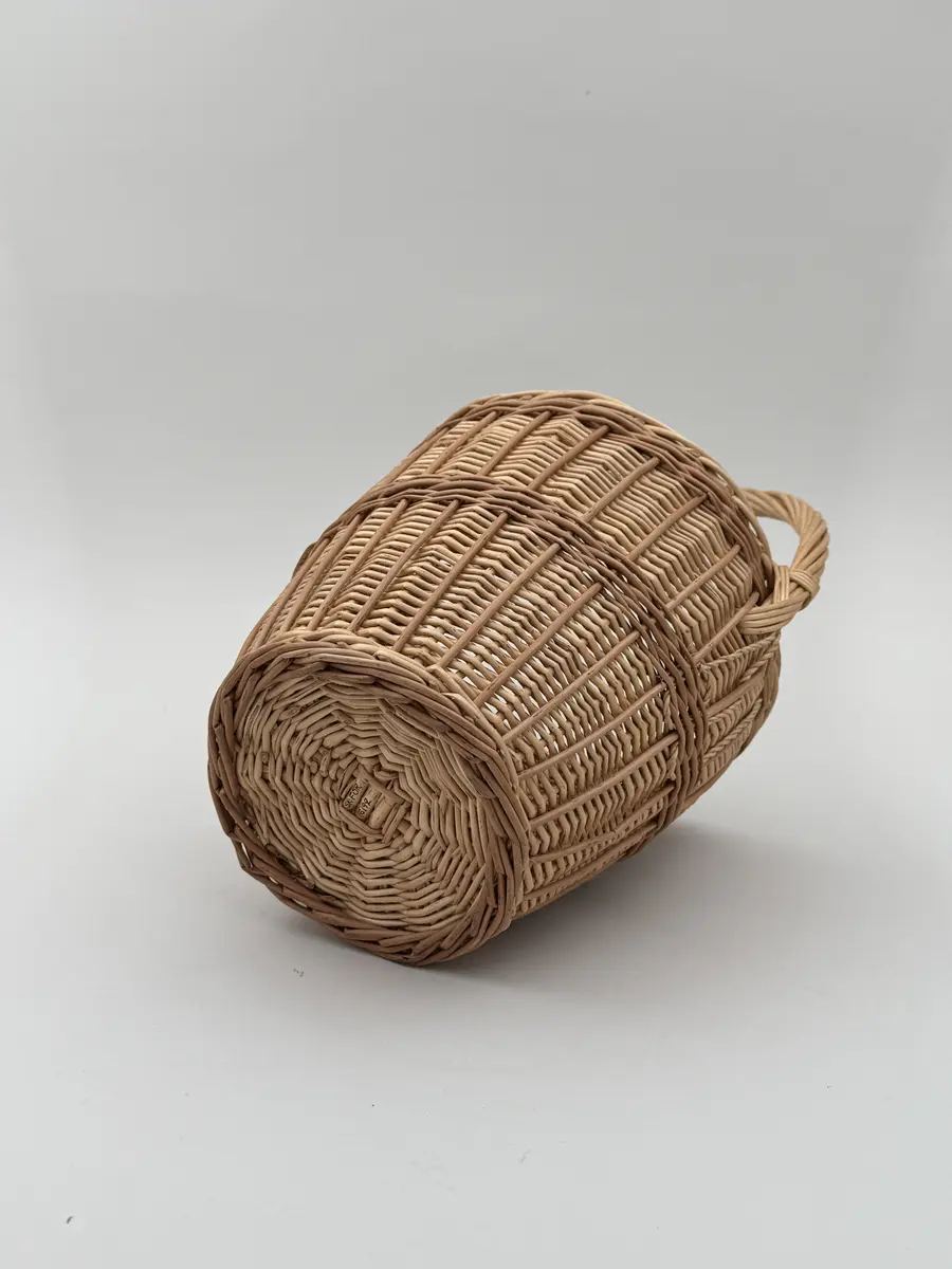 Äggkorg, handflätad av pil i två färgnyanser. Modell med ganska smal hög form. Uppsvängt handtag.