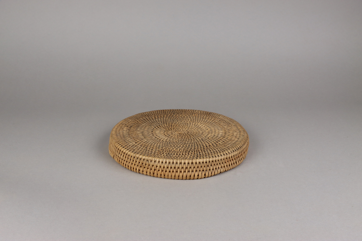 Korg bunden av kluvna rottågor över vidjor med löst lock. Rund bukig form med platt botten och platt lock.