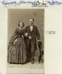 Med ledning av medföjande påskrift och folkbokföring över Vadstena, bevittnar vi sannolikt makarna Nicolaus Lignell och Sara Helena Beckman. Han född i Varberg 1831 och en första gång inflyttad till Vadstena 1848. Efter en kortare tid i Borås återkom han ånyo 1851. Då som handlardräng men efterhand skriven som handelsbokhållare och vidare som egen handlare. Fru Beckman var född i Västra Stenby 1839. De vigdes i Vadstena 1861 och flyttade permanent till Stockholm 1873. Fotografiet kan antas tillkommit under parets första tid i huvudstaden.