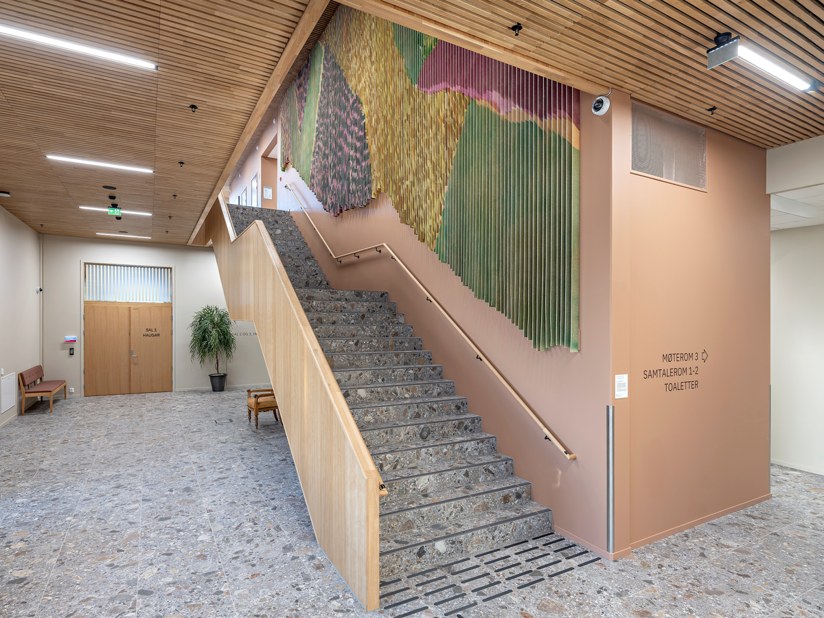 Det flate jordbrukslandskapet i Vestfold er utgangspunkt for Marianne Moes vegghengte tekstil "Landskap i bevegelse". Mengder av tjukk ullfilt er malt med store pensler, sprøytet med farger på begge sider og så skåret opp i remser. Motivet brytes derfor opp, og forandrer seg avhengig av hvor betrakteren står og hvordan hen beveger deg. Det skaper en opplevelse av et skiftende landskap, linjer og fargespill som minner om vårgrønne skoger og modne åkrer.