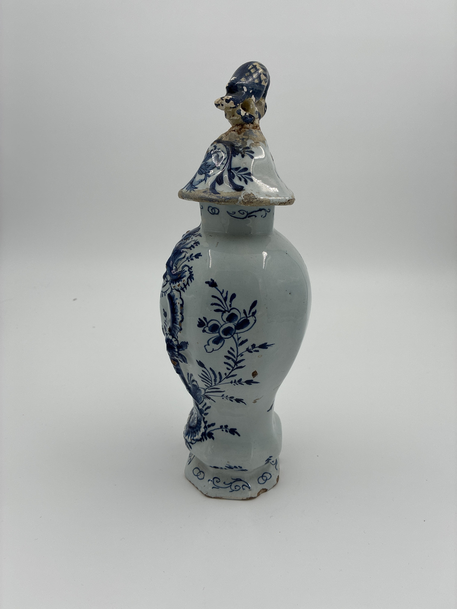 Urna med lock. Av glaserad fajans med dekor i blått. Locket dekorerad med fågel, defekt. Troligen från Delft.