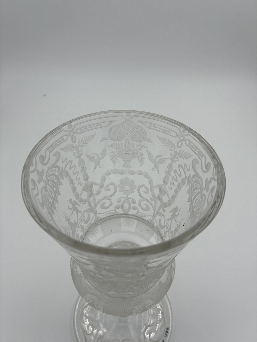 Pokal med lock. Av glas med riklig etsad dekor. 

Enligt säljarens uppgift har pokalen varit en gåva till fru von Proschwitz, Floda herrgård vid dennas 50-årsdag.
Efter hennes bortgång överlämnades pokalen som minnesgåva till dr G. Nystedt för dennas mångåriga tjänst som husläkare hos familjen Proschwitz.