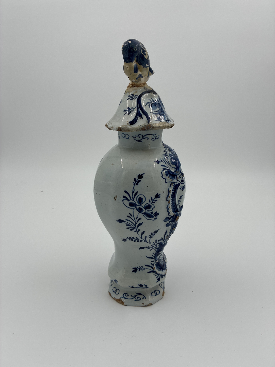 Urna med lock. Av glaserad fajans med dekor i blått. Locket dekorerad med fågel, defekt. Troligen från Delft.