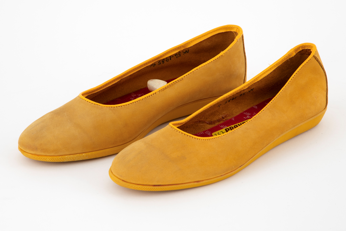 Ballerinasko med rundet tå i gult semsket skinn. Flat gummisåle med rifler. Ufôret. Den innvendig sålen er trukket med rødt stoff med hvite spetter. 
Høyre- og venstre sko har ulik størrelse.