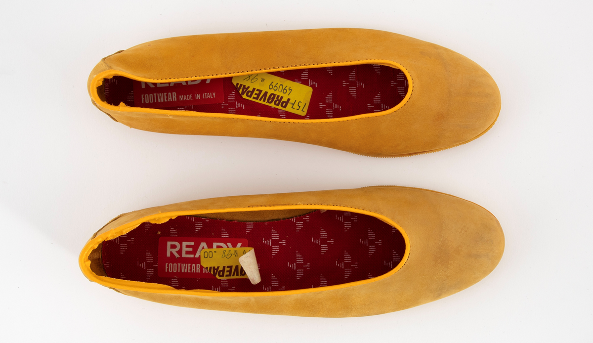 Ballerinasko med rundet tå i gult semsket skinn. Flat gummisåle med rifler. Ufôret. Den innvendig sålen er trukket med rødt stoff med hvite spetter. 
Høyre- og venstre sko har ulik størrelse.