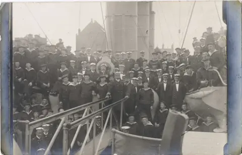 Fotopostkort. Kadetter og mannskap om bord på kadettskipet FRITJOF, kanonbåt av 1. klasse. Mulig Oskar Alf Gunvaldsen til høyre for koøyet, delvis skjult.