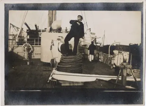 Fotopostkort. Ukjent mann står oppå en stor taukveil på dekk av kanonbåt av 1. kl. VIKING.