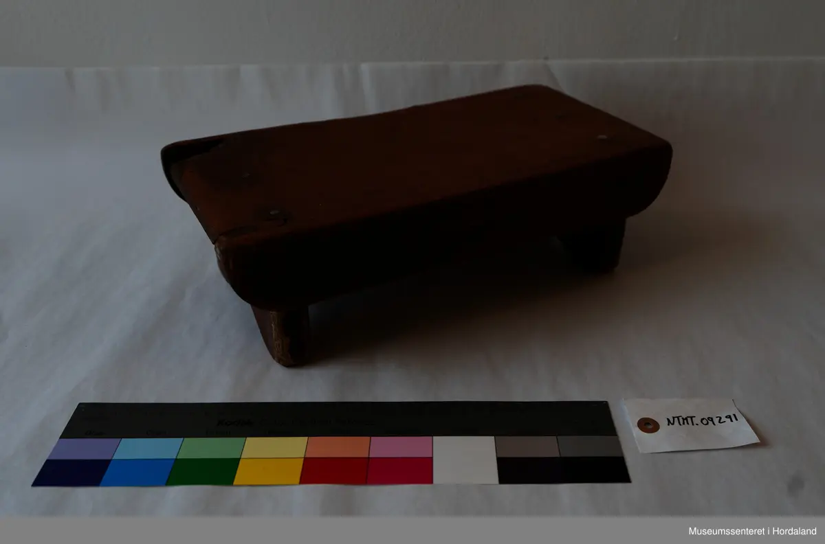 Liten, brun fotskammel av tre. 