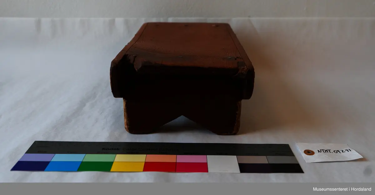 Liten, brun fotskammel av tre. 