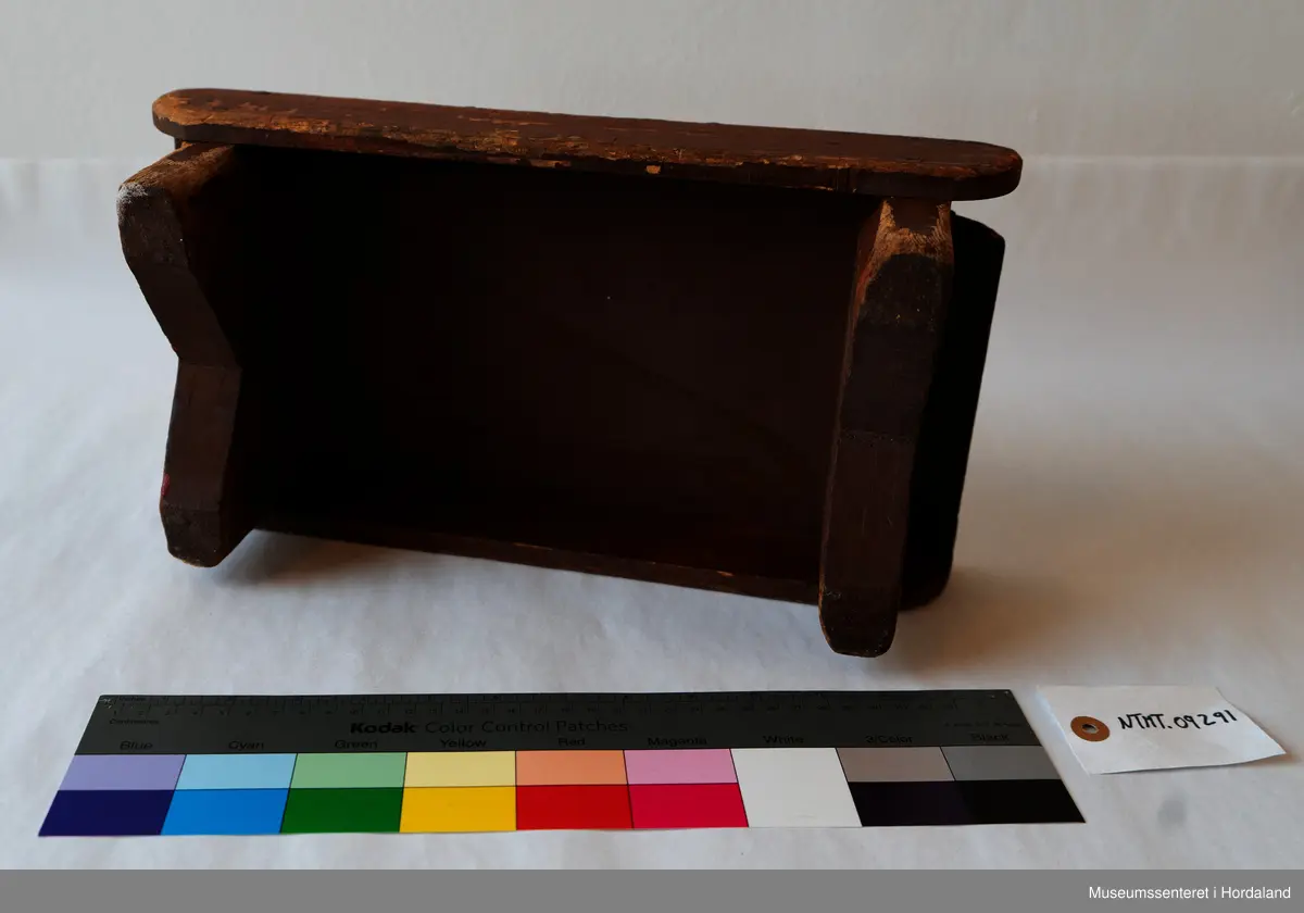 Liten, brun fotskammel av tre. 