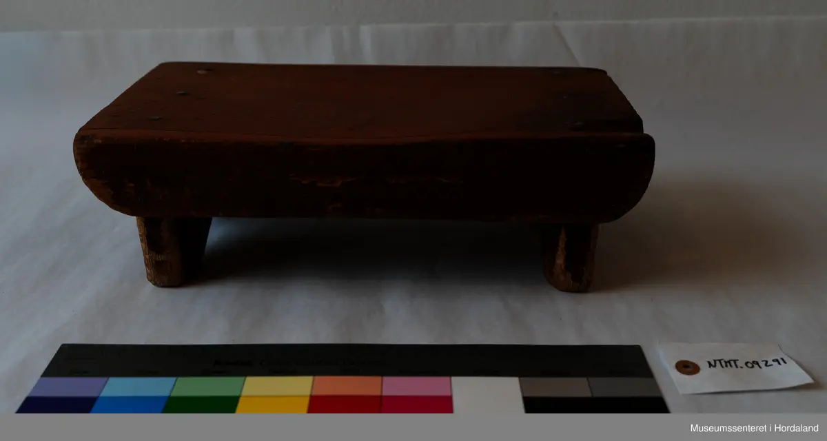 Liten, brun fotskammel av tre. 