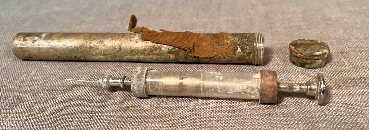 Rifle, et par gummistøvler, arbåndsur, tekstilrester, lommelykt, insulinsprøyte i metallrør, penn, kniv, slire, 13 mynter, en plastbit, hanske, 2 små glassflasker og en stor glassflaske.