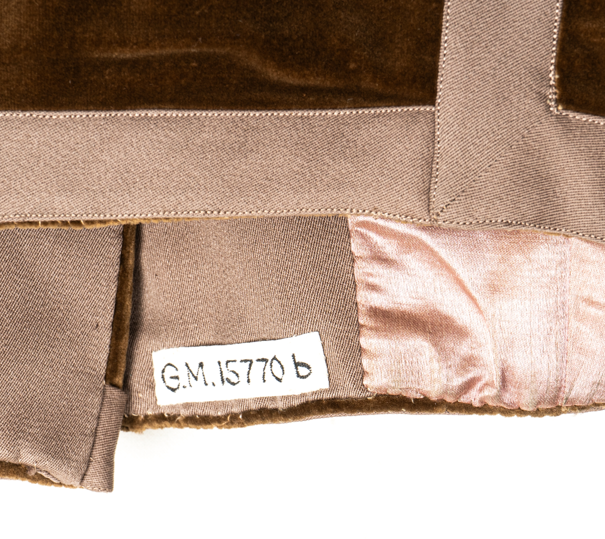 Del av dräkt/klänning.
b) Jacka, sammet. Krage och slag av gabardin med blommor av sammet. Knäppning fram. Långa puffärmar med slag. livet och ärmarna dekorerade med gabardinremsor. L fram 43cm, bak 37cm.