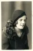 Porträtt av kvinna med en cloche-hatt och kappa med pälskrage.