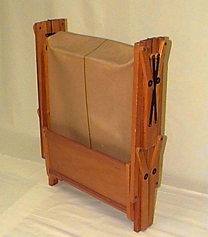 Rektangulär ram av lackerat trä. På båda kortsidorna sitter en rektangulär träskiva, höjd 287 mm, bredd 640 mm. Fyra ben utmed vardera långsida, fastsatta med skruv. Dessa ben är rörliga och sängen kan tryckas ihop, kortsida mot kortsida så att den ryms på liten yta. Sängbotten av brun juteväv med grön rand i mitten från kortsida till kortsida. I sängbotten på ena kortsidan sitter oval metall skylt med text "Wassbergs patent". Två svarta metallbågar under sängbotten och ett krysstag av svart metall på båda långsidornas mitt.