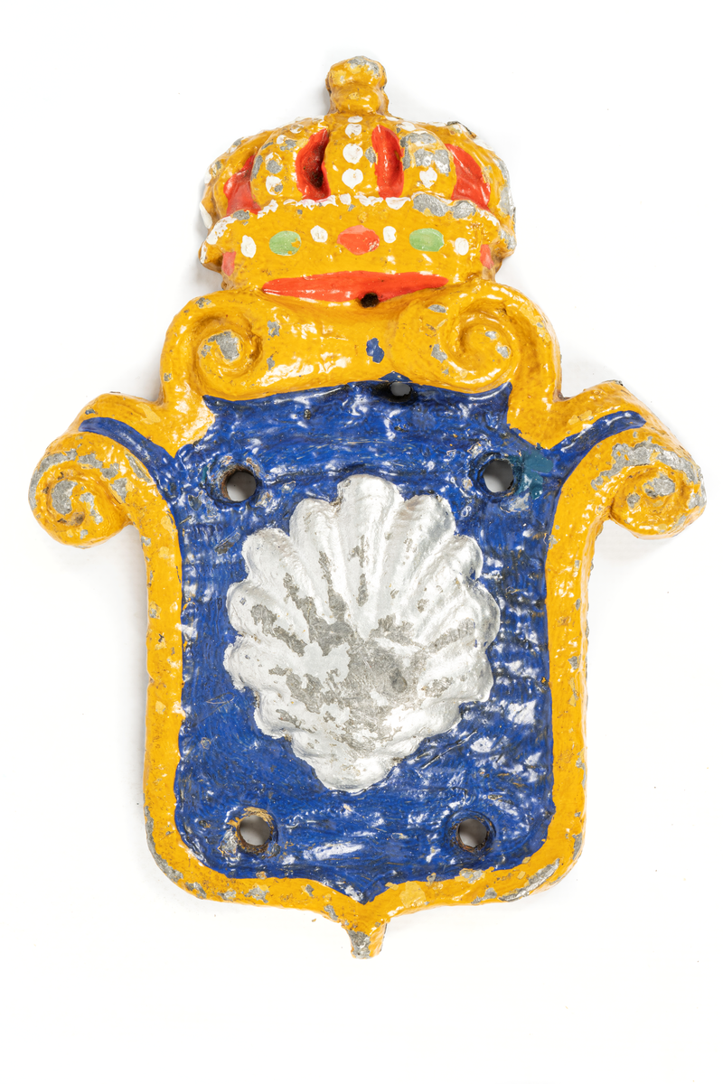 Består av sköld med krona, inom skölden på blå botten snäckskal, bronserat i vitt. Kanterna på skölden målade i gult, kronan i gult, rött och vitt.