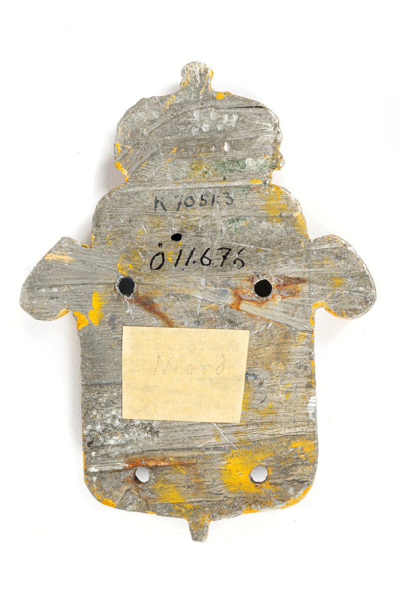 Består av sköld med krona, inom skölden på blå botten snäckskal, bronserat i vitt. Kanterna på skölden målade i gult, kronan i gult, rött och vitt.