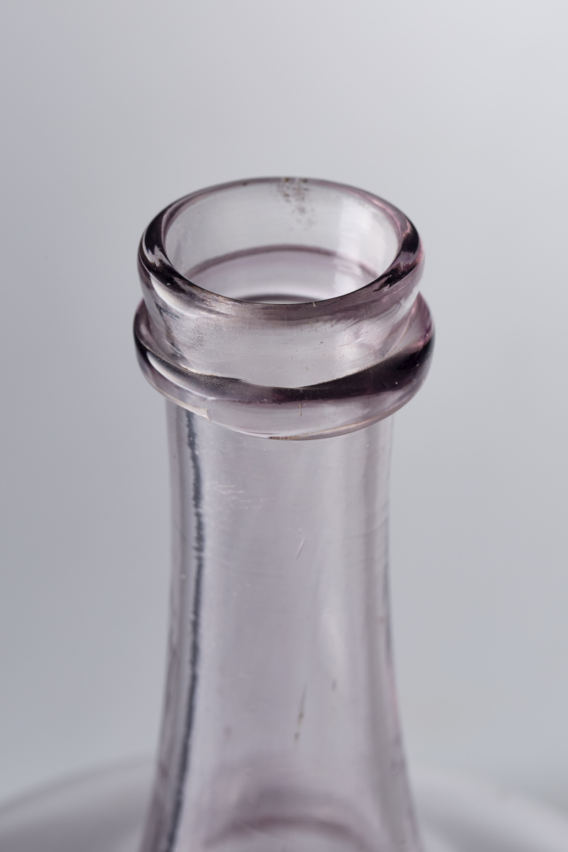 Karaffel med påsmeltet ring rundt kragen og pontmerke. Enkel gravering. Glasset er ikke helt klart, men har en anelse mangan.